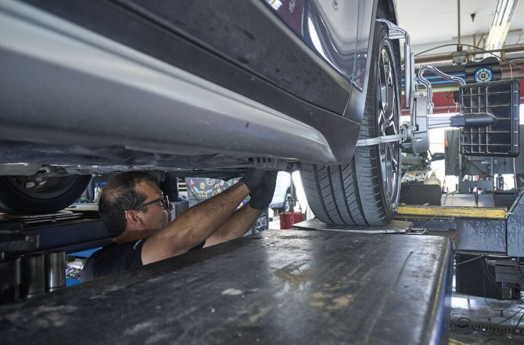 Technician performing a computerized wheel alignment at Patriot Express Tire & Oil in Plano, Texas.