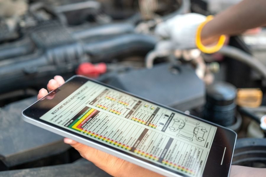 Person holding a tablet displaying a multi-point vehicle inspection form